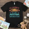 My Favorite Child Is My Middle Daughter text in colorful, retro font on a black t-shirt
