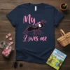 My Loves Me t-shirt design with a mother ant carrying a baby ant, featuring pink text and graphics on a