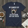 My Siamese Cat Tilts Its Head Just Like You Do t-shirt featuring a cartoon Siamese cat with bright blue eyes
