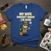 My Wife Doesn't Know I'm Here funny quote t-shirt with a cartoon man hiding with a plant and phone