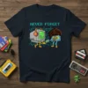 Never Forget t-shirt with pixelated text, cartoon computer with headphones, and a cassette tape character holding a controller