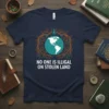 Navy t-shirt with white text "NO ONE IS ILLEGAL ON STOLEN LAND" inside a circular design featuring the Earth and