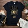 Black t-shirt with gold NOLA NEW ORLEANS text and a vintage lamp post crest graphic, featuring a fleur-de-lis emblem