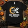 Nom Nom Nom Happy Halloween t-shirt with a graphic of a pumpkin eating ghosts