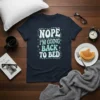 Nope I'm Going Back to Bed text design on a navy blue t-shirt, featuring white and teal retro-style lettering