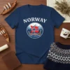 Norway Viking Ship T-Shirt featuring a graphic of a Viking longship with the Norwegian flag, mountains, and trees