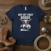 Not My First Rodeo quote t-shirt with cowboy on a bucking horse and bull skull graphic