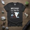 Dark heather t-shirt with white text "NOTE TO SELF: Let Shit Go" and a graphic of a person pushing a