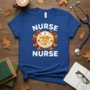 Blue t-shirt with "Nurse Nurse" text and a circular fall-themed design featuring a caduceus symbol, pumpkins, and leaves