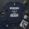 Nursing Is A Work Of Heart T-Shirt featuring white text and a heart with a heartbeat line