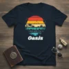 Oasis t-shirt design with a retro sunset, palm trees, cacti, and a tranquil body of water