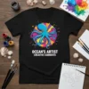 Black t-shirt with a blue octopus and the text "OCEAN'S ARTIST CREATIVE CURRENTS" in white, surrounded by colorful paint splatters