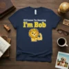 Of Course I'm Amazing I'm Bob t-shirt with a flexing lion graphic and crown, featuring white and yellow text
