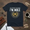 Navy t-shirt with "OF COURSE I'M RIGHT I'M MIKE" text and a gold laurel wreath with crown graphic