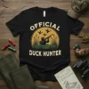 Official Duck Hunter t-shirt design featuring a hunter in a blind with ducks flying overhead and the text "OFFICIAL DUCK