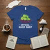Official Sleep Shirt design with cute sleeping caterpillars piled on a pillow. Features text "OFFICIAL SLEEP SHIRT" in white