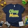 Navy blue t-shirt with "Okay Mom." text in green and yellow, featuring a playful font