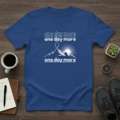 Royal blue t-shirt with white text "one day more" repeated and a graphic of a hiker on a mountain peak