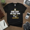 Black t-shirt with white and yellow text "ONE DAY OR DAY ONE YOU DECIDE" and an upward arrow graphic