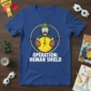 Operation: Human Shield text on a blue t-shirt with a cartoon soldier holding a cracked shield in crosshairs