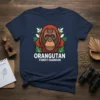 Orangutan Forest Guardian text design with a stylized orangutan face and green leaves on a navy t-shirt