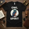 Black t-shirt with white text "OWL SPIRIT" and a colorful, stylized owl perched on a branch against a moon background