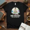 Black t-shirt with "Own Your Nest Own Your Knowledge" text and cute owls sitting on books, graduation cap graphic