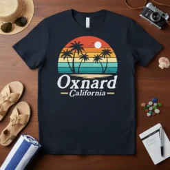 Oxnard California text with retro sunset and palm trees graphic on a dark t-shirt
