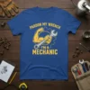 Blue t-shirt with yellow text "Pardon My Wrench I'm A Mechanic" and graphic of a muscular arm holding a wrench