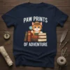 Paw Prints Of Adventure t-shirt design with a cat holding a magnifying glass over a stack of books