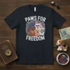 Paws For Freedom text on a dark t-shirt with a graphic of five dogs wearing bandanas and sunglasses, superimposed over