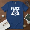 Peace Dove Heart Hands T-Shirt design with bold white text "PEACE" above a graphic of white hands forming a heart
