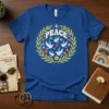 Peace Dove Wreath Graphic Tee with bold "PEACE" text, white doves, and colorful flowers in a laurel wreath design