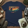 Retro PENSSYLVANIA t-shirt design featuring a silhouette of Bigfoot walking through a forest at sunset
