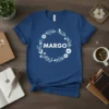 Blue t-shirt with "MARGO" in white text surrounded by a floral and leaf wreath design with teal and white accents