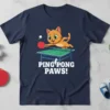PING PONG PAWS! text on a navy t-shirt with a cartoon orange cat playing table tennis