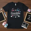 Pink or Blue Grandma Loves You text design with hearts and baby-themed graphics on a black t-shirt