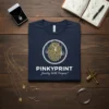 Navy t-shirt with "PINKYPRINT Jewelry With Purpose" text and a fingerprint graphic with hanging jewelry, suitable for jewelry designers