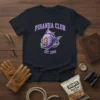 Piranha Club Est. 2000 text with cartoon piranha graphic on a navy t-shirt