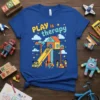 Blue t-shirt with yellow and teal text "PLAY is therapy" above a colorful playground scene with children playing, clouds, and