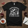 Black t-shirt with white text "poetry teatime is totally my jam" above an open book, tea cup, and jam jar
