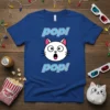 Blue t-shirt with "pop! pop!" text and a surprised white cat face graphic, featuring pink ears and blue outline