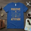 Blue t-shirt with orange text "POSITIVE ATTITUDE" and a rocket ship graphic, symbolizing ambition and motivation