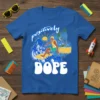Blue t-shirt with "positively DOPE" text and a surfer riding a wave illustration, featuring palm trees and a sunset