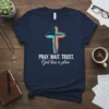 Christian t-shirt with colorful brush stroke cross and text "PRAY. WAIT. TRUST. God has a plan."