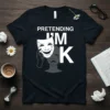 Pretending I'm K quote with a smiling mask covering a sad face on a black t-shirt design