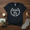 Prioritize Home Harmony text with a minimalist house graphic inside a laurel wreath on a black t-shirt