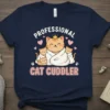 Professional Cat Cuddler text with cute cartoon cat family graphic on a navy blue t-shirt
