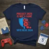 Navy blue t-shirt with red text "PROJECT 2025 IS NOT A GAME" above a blue shield with red gears and