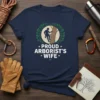 Proud Arborist's Wife t-shirt with a silhouette of a climber on a tree, surrounded by a laurel wreath and stars